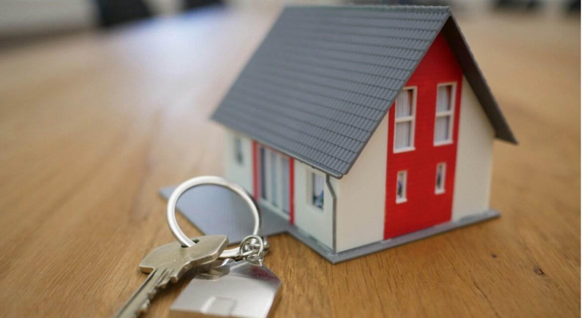 House keys beside model property on wooden table