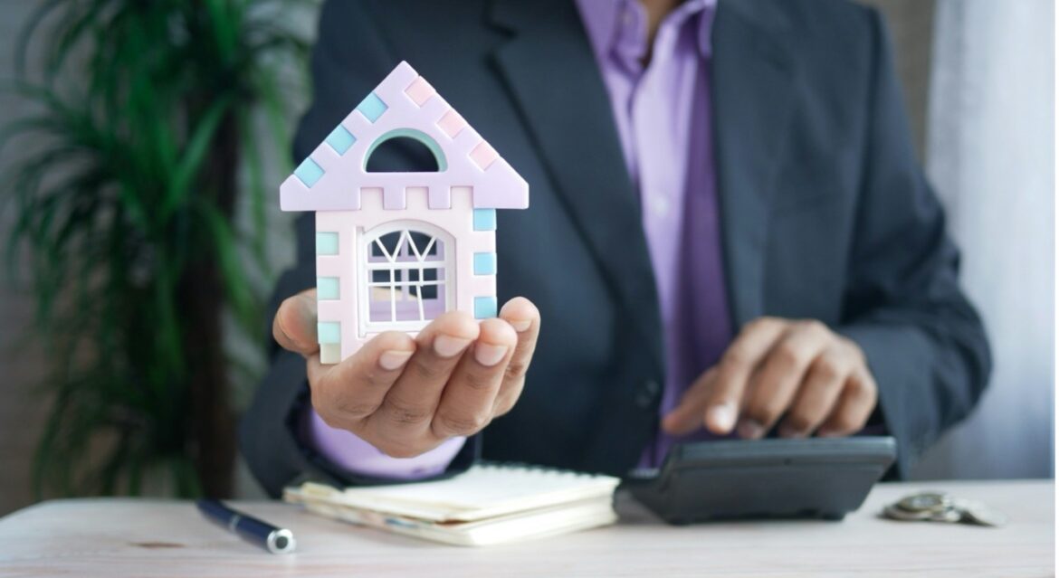 Mortgage advisor holding model house with calculator