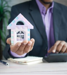 Mortgage advisor holding model house with calculator
